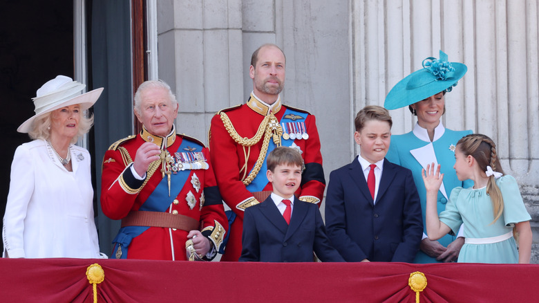 Princess Charlotte turns to speak to Kate Middleton as the royal family stands on the Buckingham Palace balcony during Trooping the Colour 2025