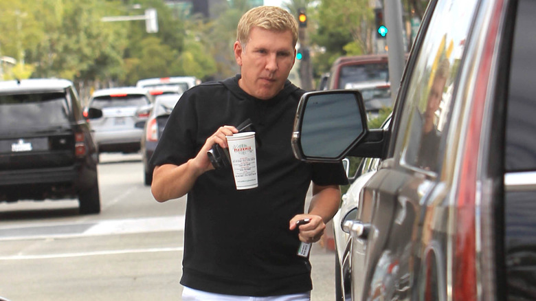 Todd Chrisley heading to his car holding a takeaway cup.